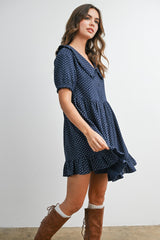 woman wearing a navy blue short sleeve dress with white polka dots and ruffled hem, paired with tan knee-high boots