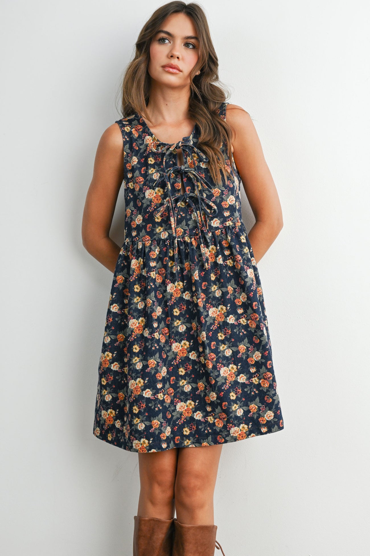 woman wearing a navy floral print sleeveless dress with a gathered skirt and adjustable drawstring neckline