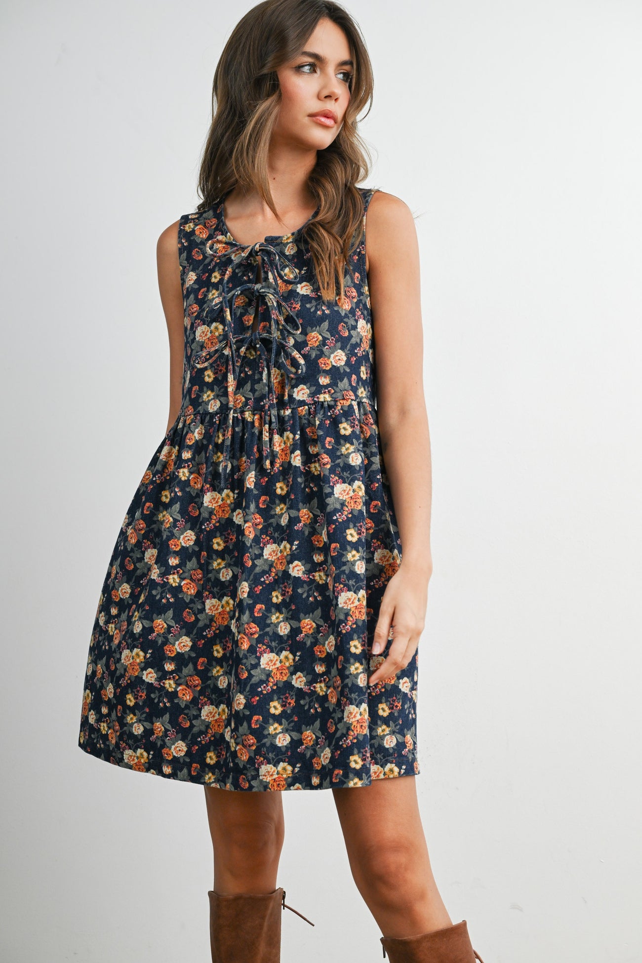 woman wearing a navy floral sleeveless dress with a tie detail at the neckline and a flared skirt