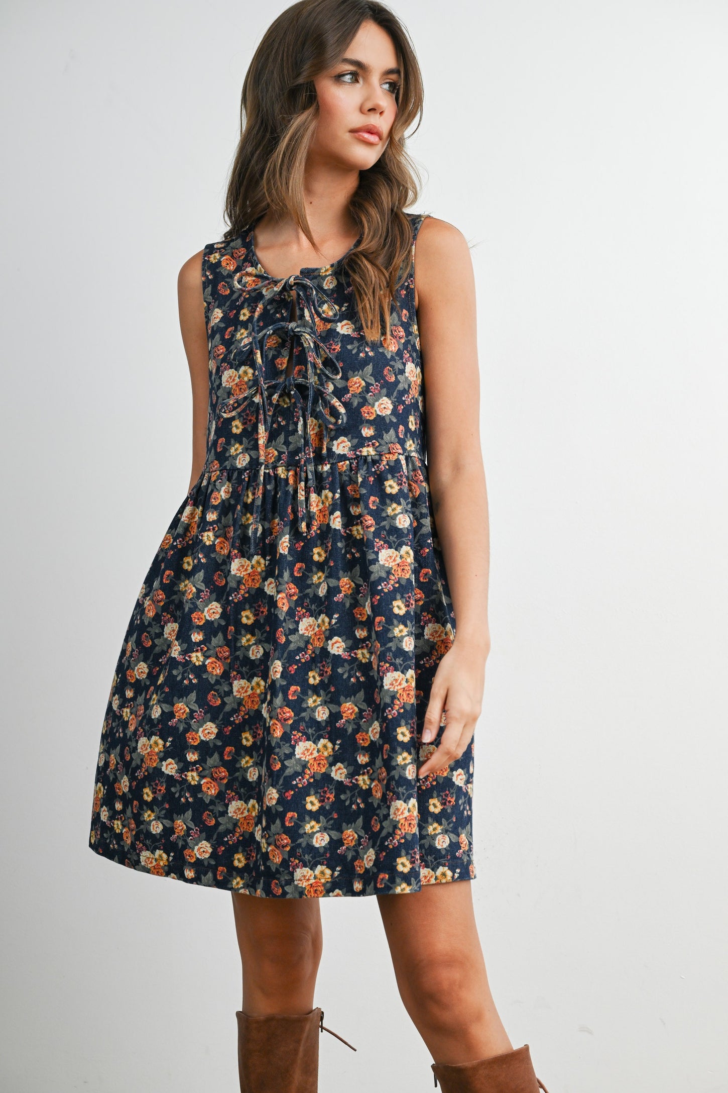 woman wearing a navy floral sleeveless dress with a tie detail at the neckline and a flared skirt