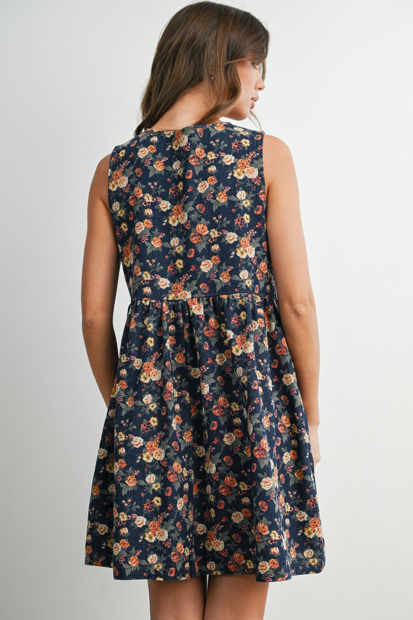 woman wearing a navy floral sleeveless dress with a fitted bodice and flared skirt, seen from the back