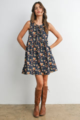 woman wearing a navy floral sundress with bow detail and pockets, paired with brown knee-high boots