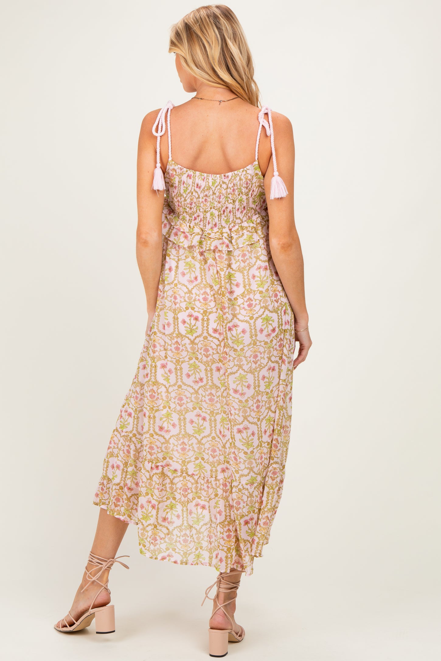 woman wearing a pink and green floral maternity maxi dress with adjustable tie straps and a flowing skirt