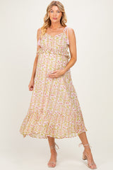 woman wearing a pink floral maternity dress with ruffled straps and a flowing skirt, holding her baby bump