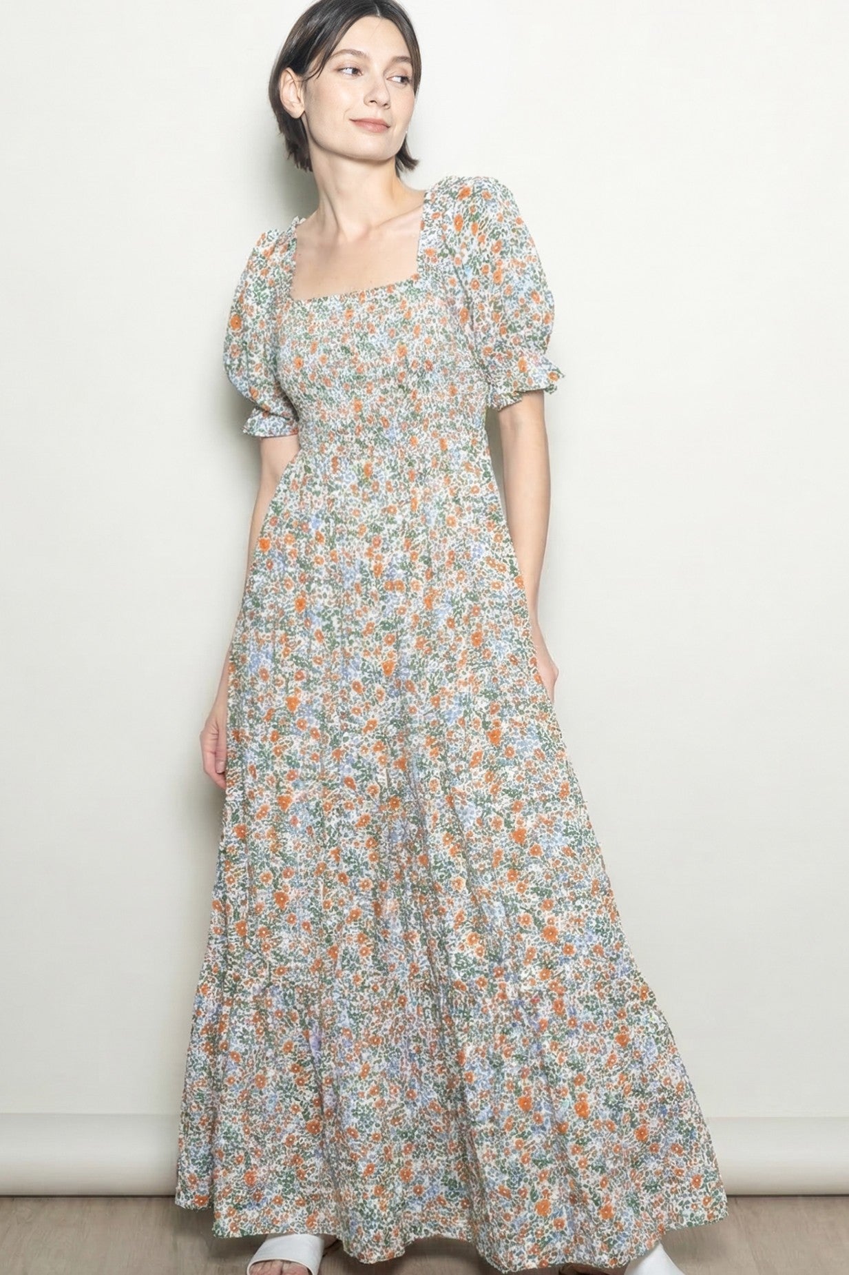 woman wearing a floral print maxi dress with square neckline and puff sleeves, standing against a light background