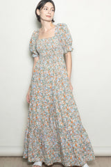 woman wearing a floral print maxi dress with square neckline and puff sleeves, standing against a light background
