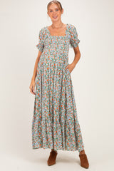 woman wearing a floral print maxi maternity dress with short puff sleeves and pockets, showing her baby bump