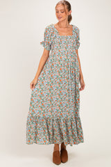 woman wearing a floral maxi maternity dress with short sleeves and a square neckline, showing her baby bump