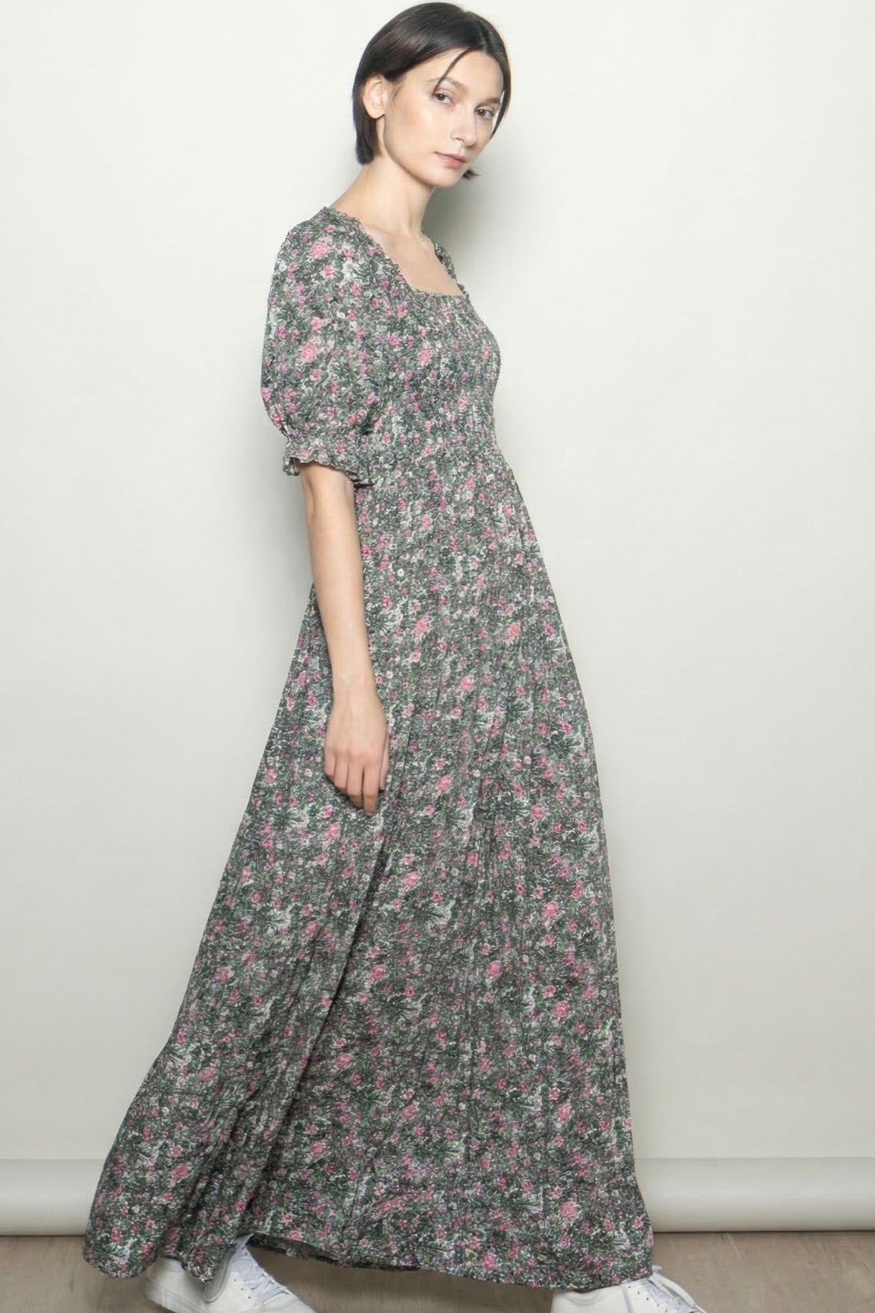 woman wearing a long floral maxi dress with puff sleeves and a square neckline, standing against a neutral background