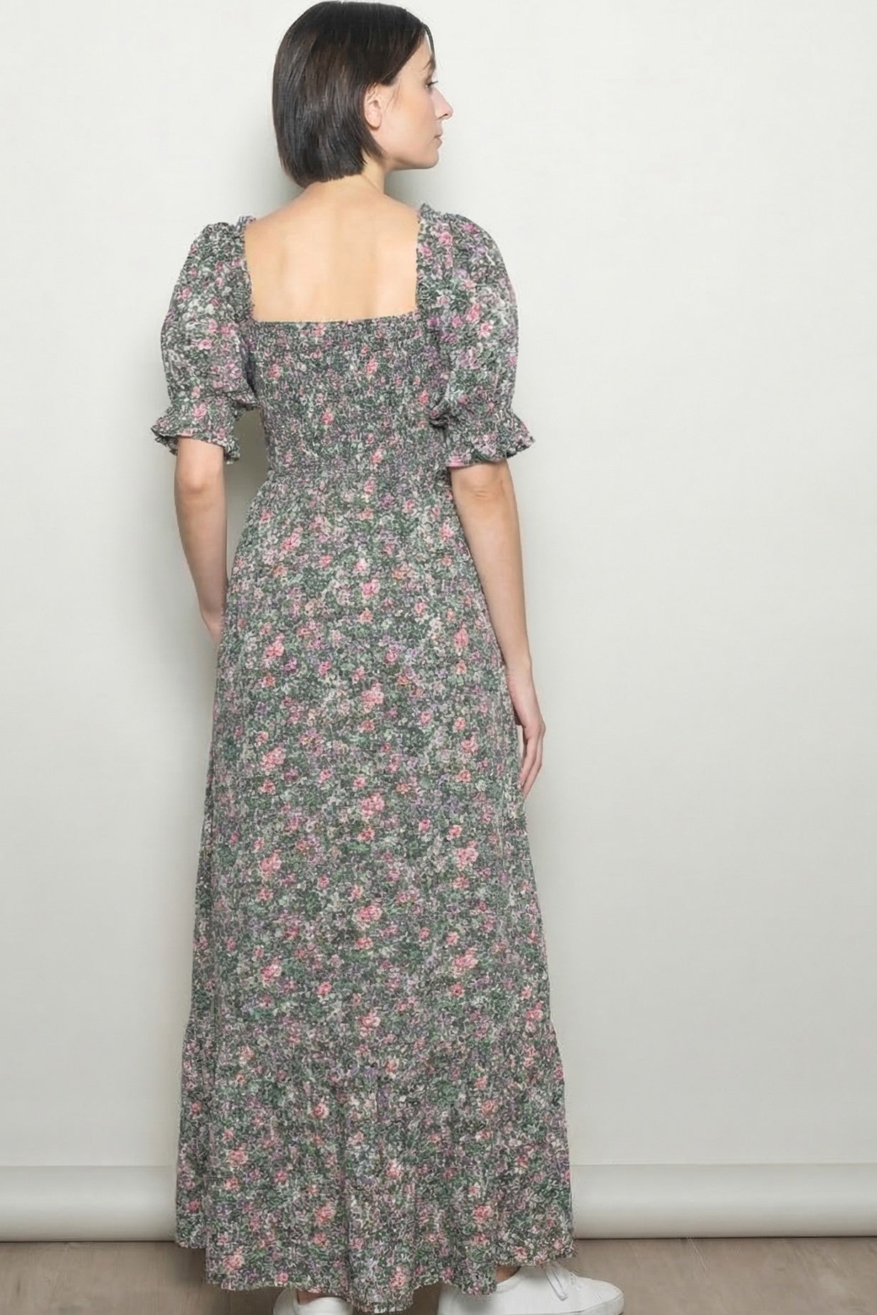 woman wearing a back view of a floral maxi dress with puff sleeves and a ruffled hemline