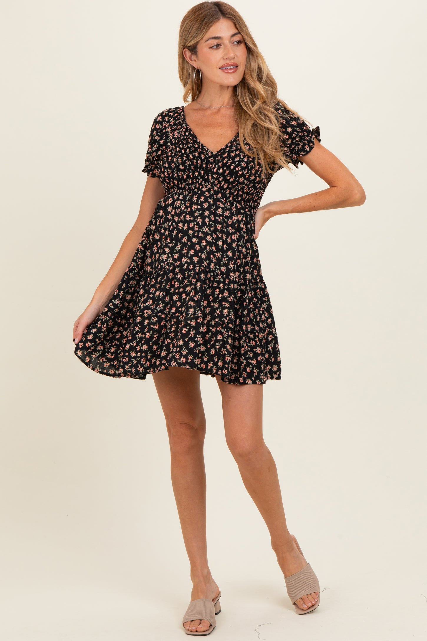 woman wearing a black floral maternity dress with short sleeves and a flared skirt, showcasing a baby bump