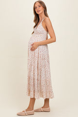 woman wearing a white floral maternity dress with a flowy skirt and holding her baby bump