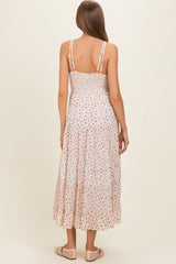 woman wearing a floral print maternity maxi dress with a tiered skirt and adjustable straps, showing a baby bump