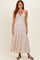 woman wearing a floral print maxi dress with spaghetti straps and a fitted bodice, standing on a neutral background