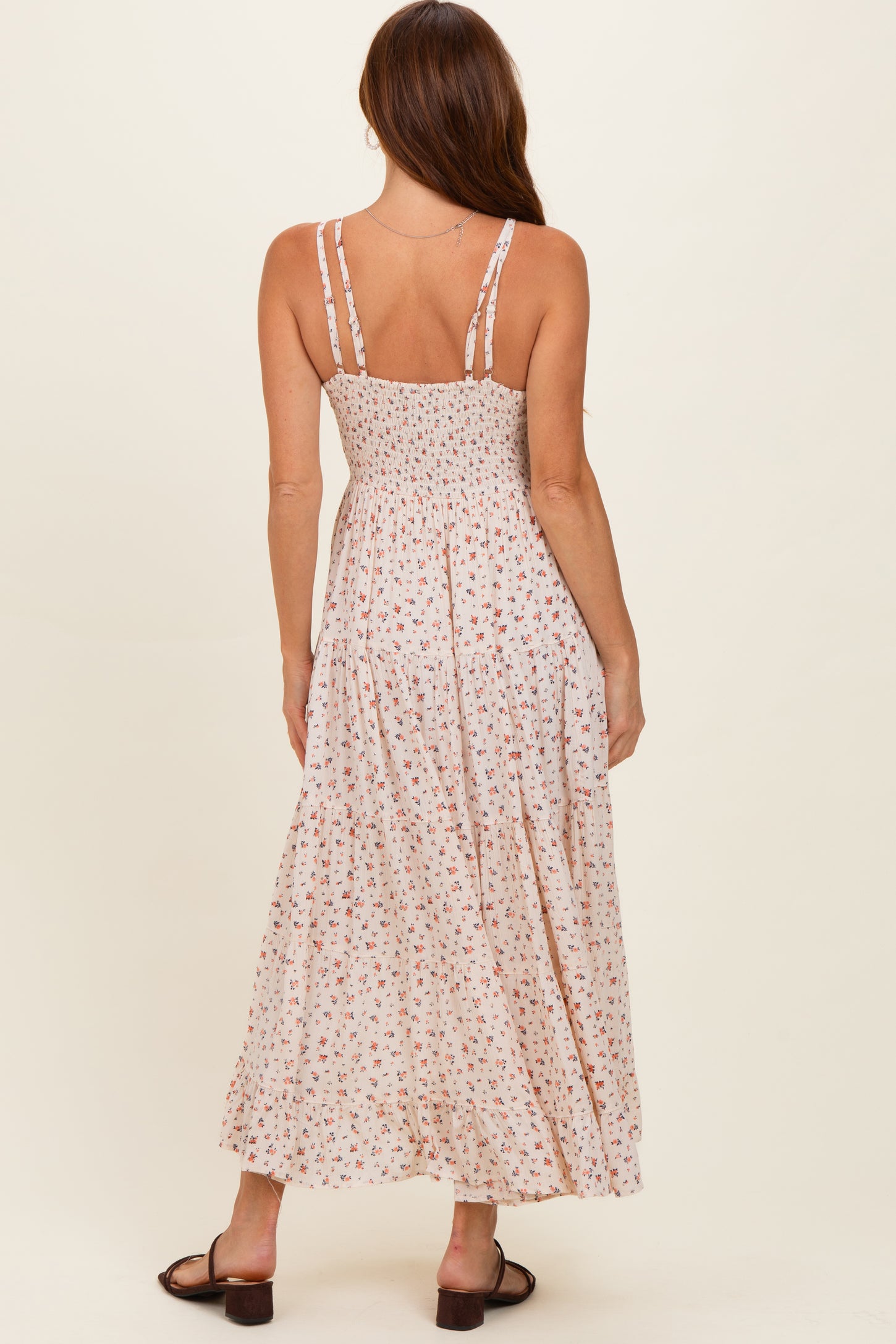 woman wearing a floral print maxi dress with adjustable straps, shown from the back