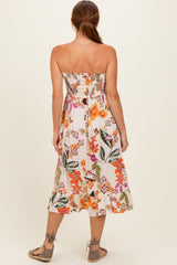 woman wearing a floral strapless midi dress with a smocked bodice and a flared hem, seen from the back