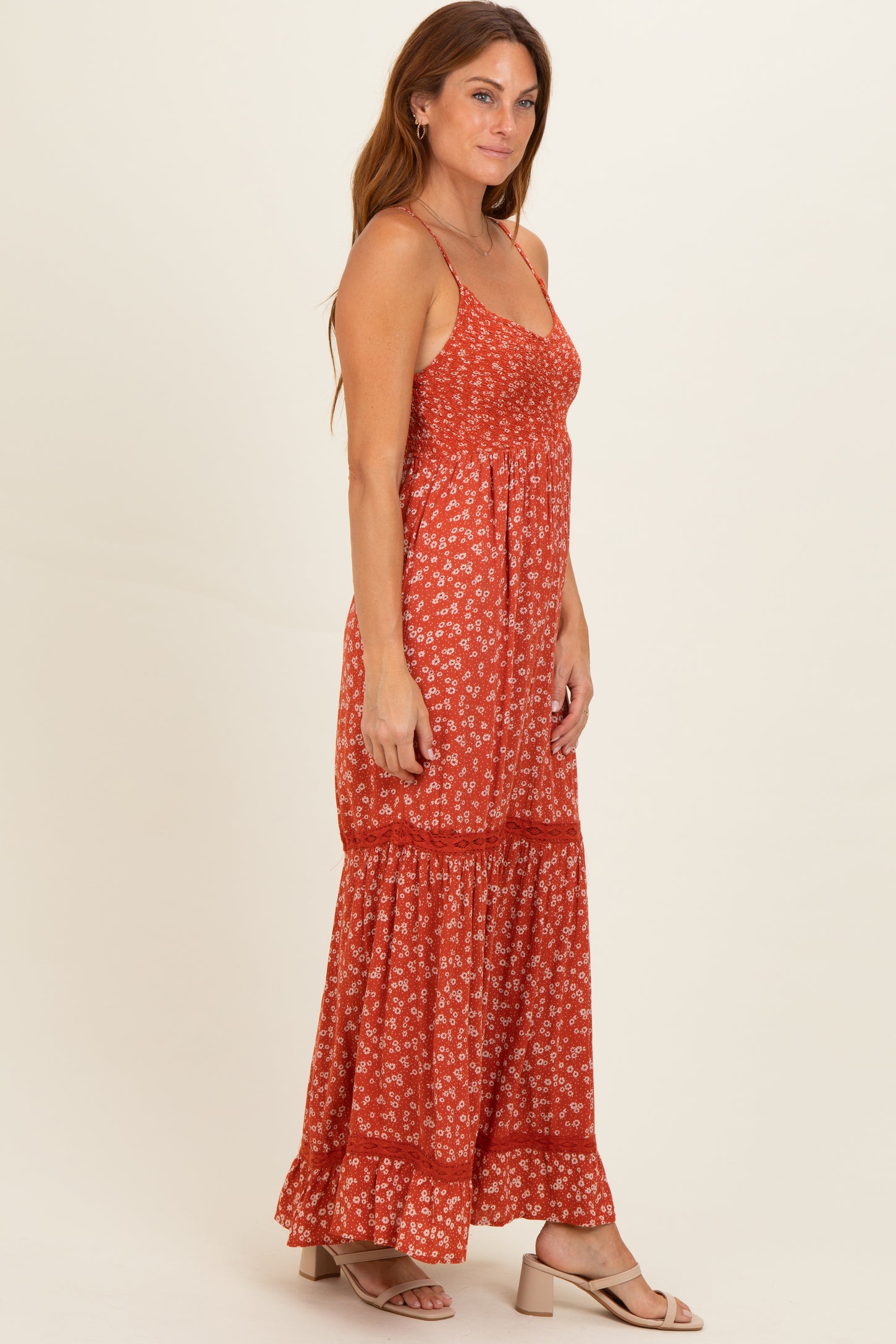 woman wearing a red floral maxi dress with a tiered skirt and adjustable spaghetti straps