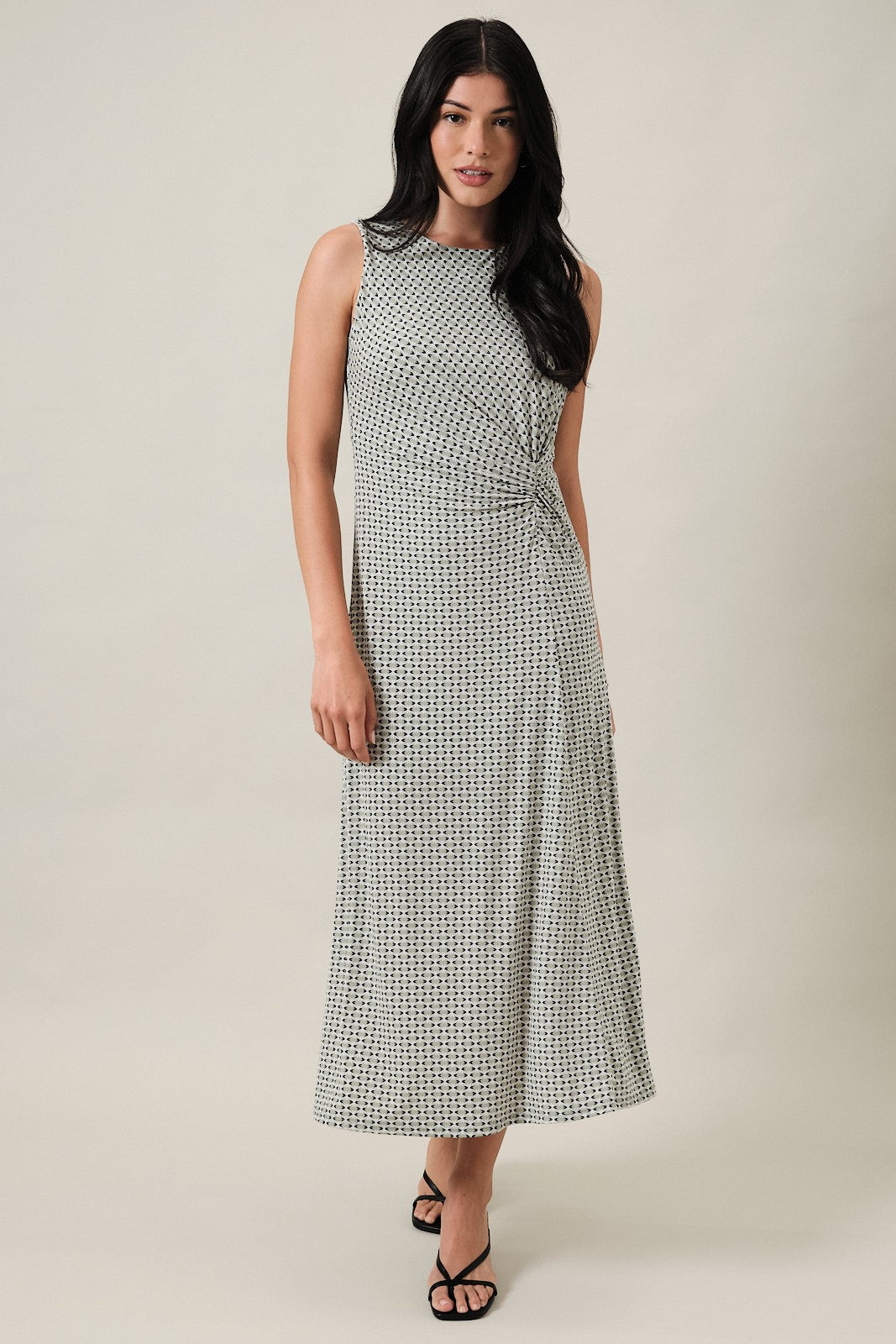woman wearing a sleeveless midi dress with a wrap style and geometric print in green and white
