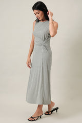 woman wearing a sleeveless black and white patterned midi dress with a knotted waist and side slit