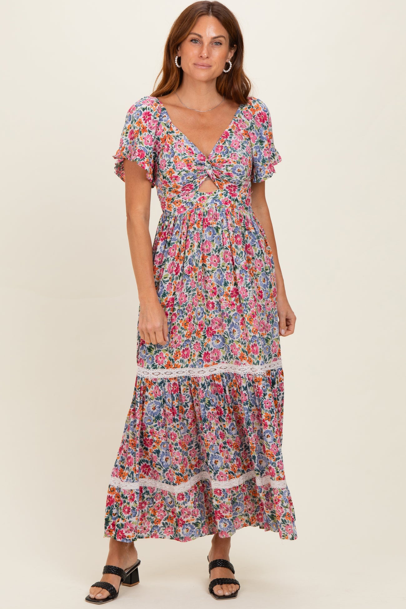 woman wearing a colorful floral maxi dress with short flutter sleeves and a tiered skirt