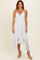 woman wearing a white lace midi dress with a v-neck and asymmetrical hemline, standing on a neutral background