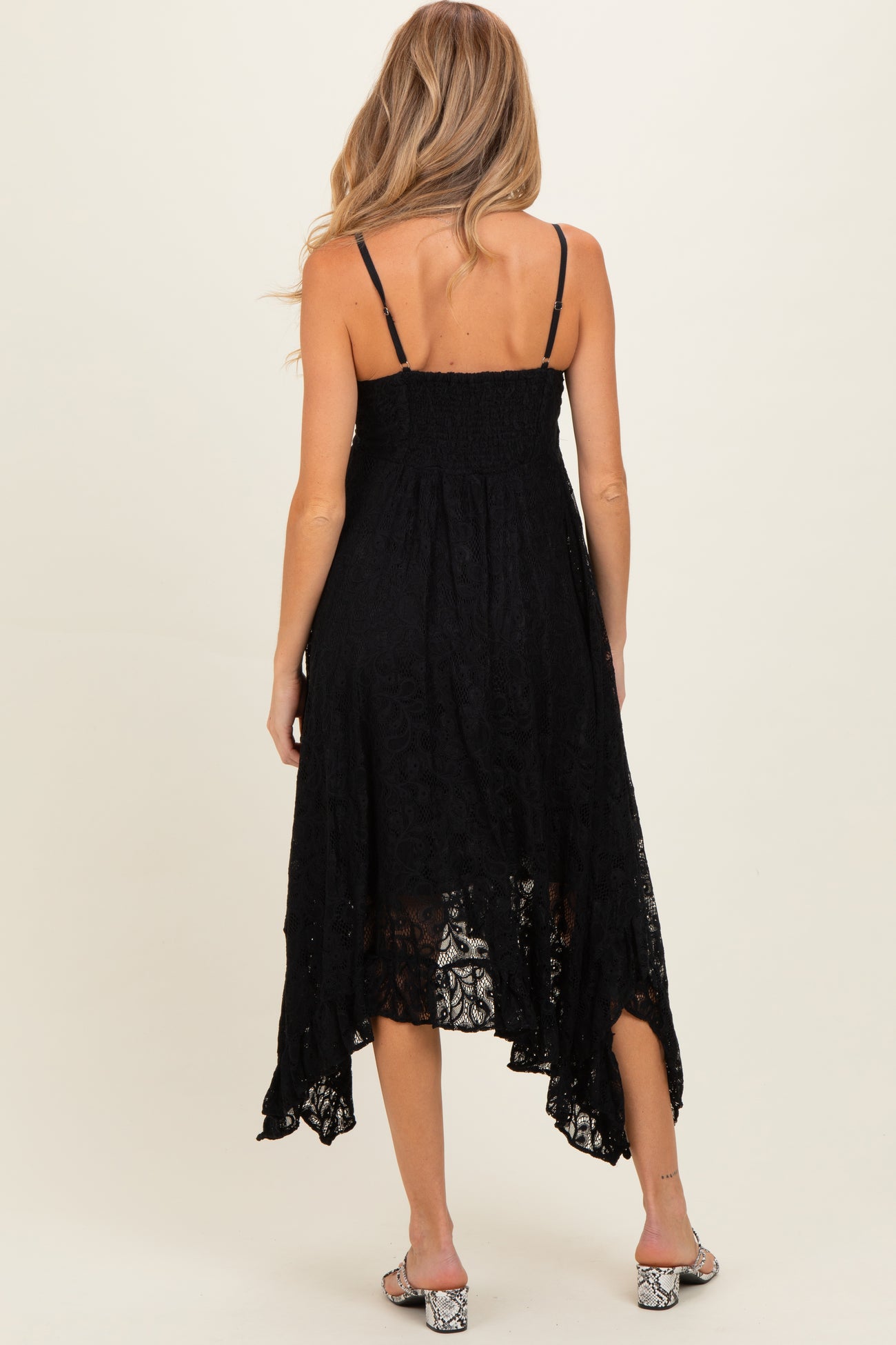 woman wearing a black lace maternity dress with adjustable straps and a high-low hem, showing a relaxed fit