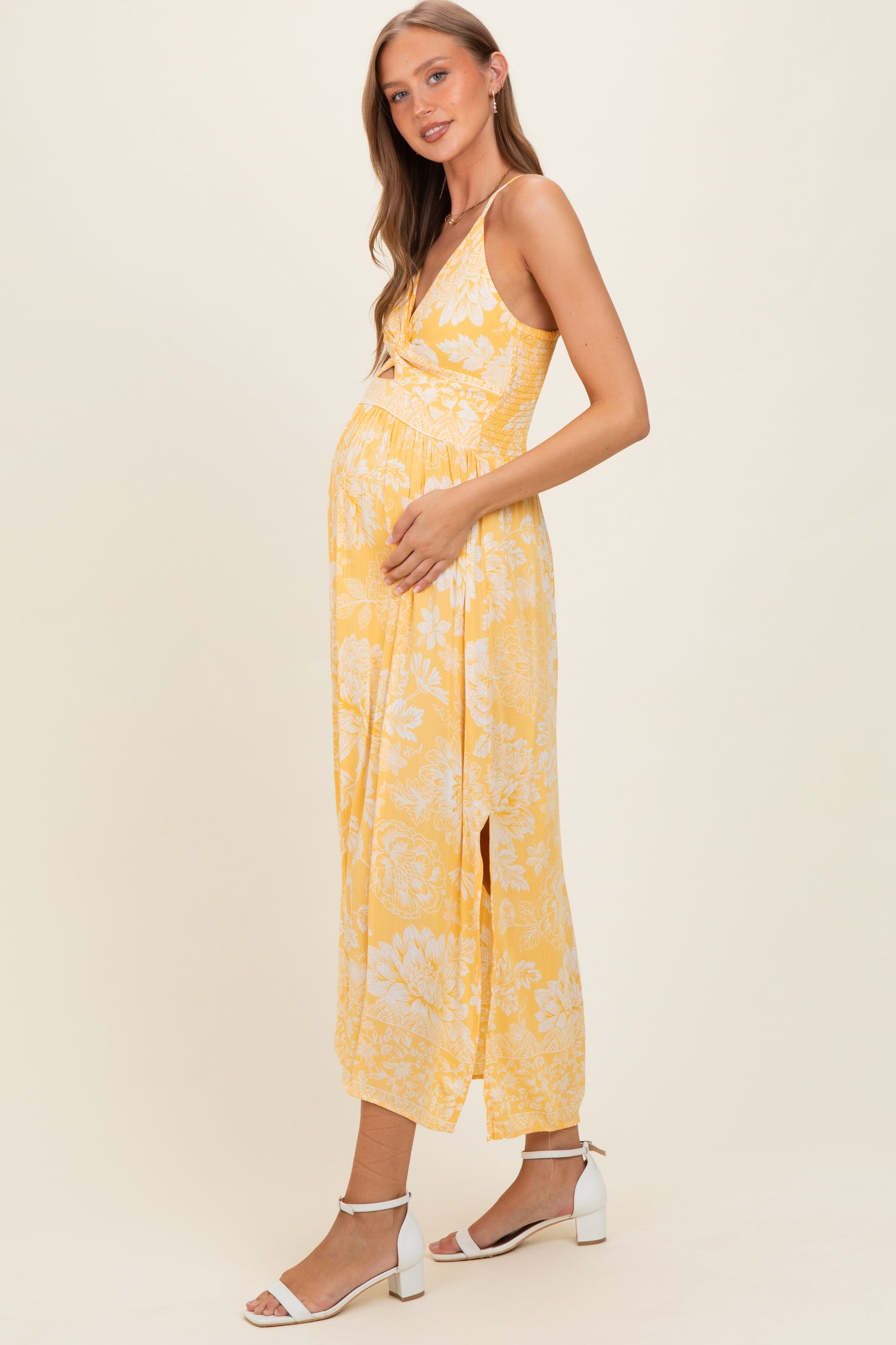 woman wearing a yellow floral maternity maxi dress and holding her baby bump