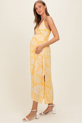 woman wearing a yellow floral maternity maxi dress and holding her baby bump