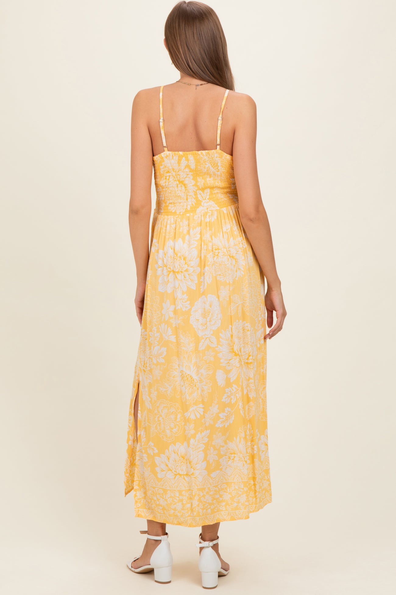 woman wearing a yellow floral maternity maxi dress with spaghetti straps and side slits