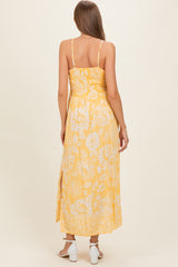 woman wearing a yellow floral maternity maxi dress with spaghetti straps and side slits