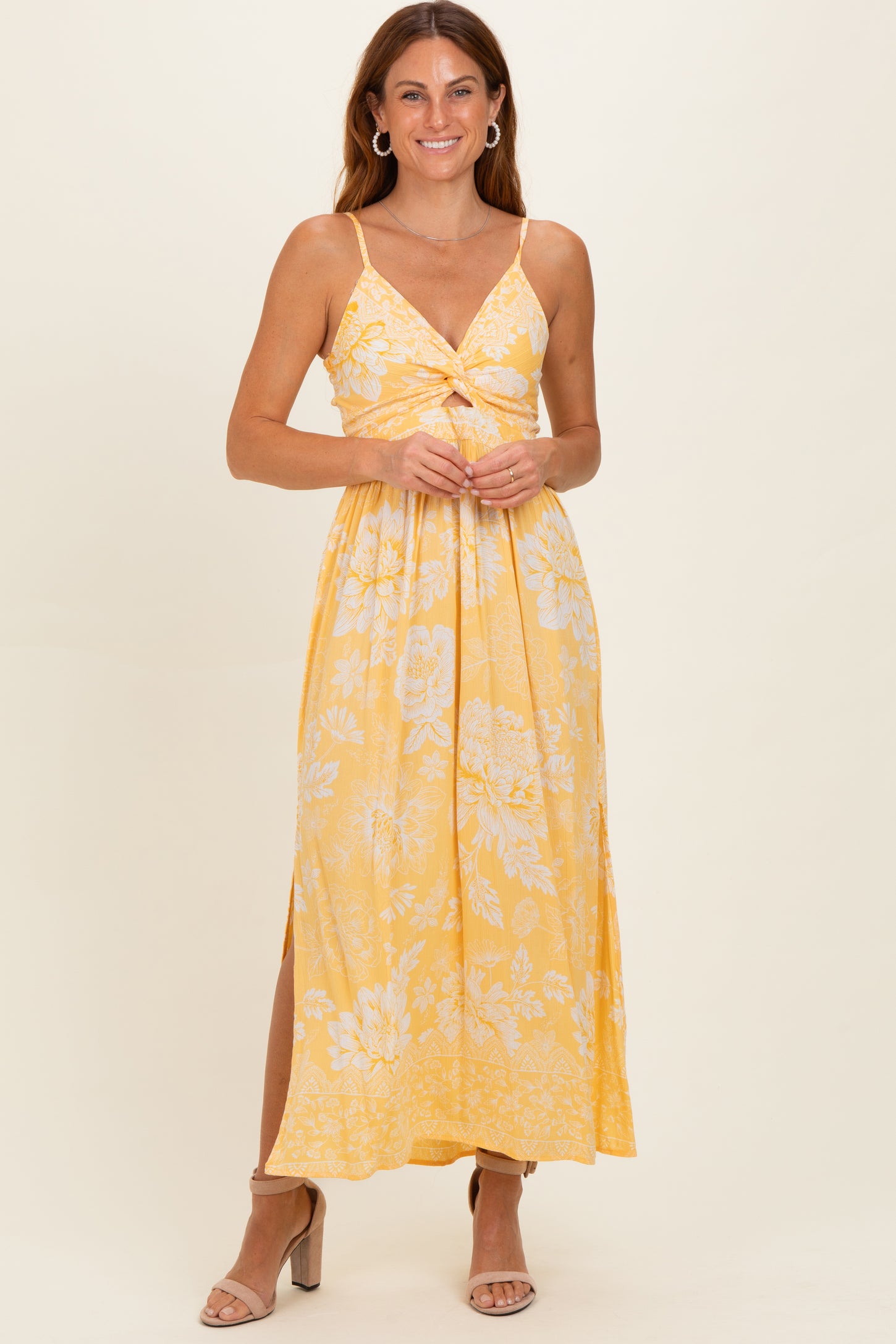 woman wearing a yellow floral maxi dress with a knotted front and side slits, smiling against a neutral background