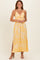 woman wearing a yellow floral maxi dress with a knotted front and side slits, smiling against a neutral background