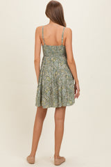 woman wearing a green floral maternity dress with a smocked back and adjustable straps, showing a baby bump