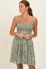 woman wearing a green patterned maternity dress with a fitted bodice and flowy skirt
