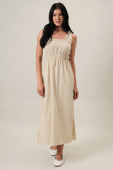 woman wearing a beige striped maxi dress with a fitted waist and side slits