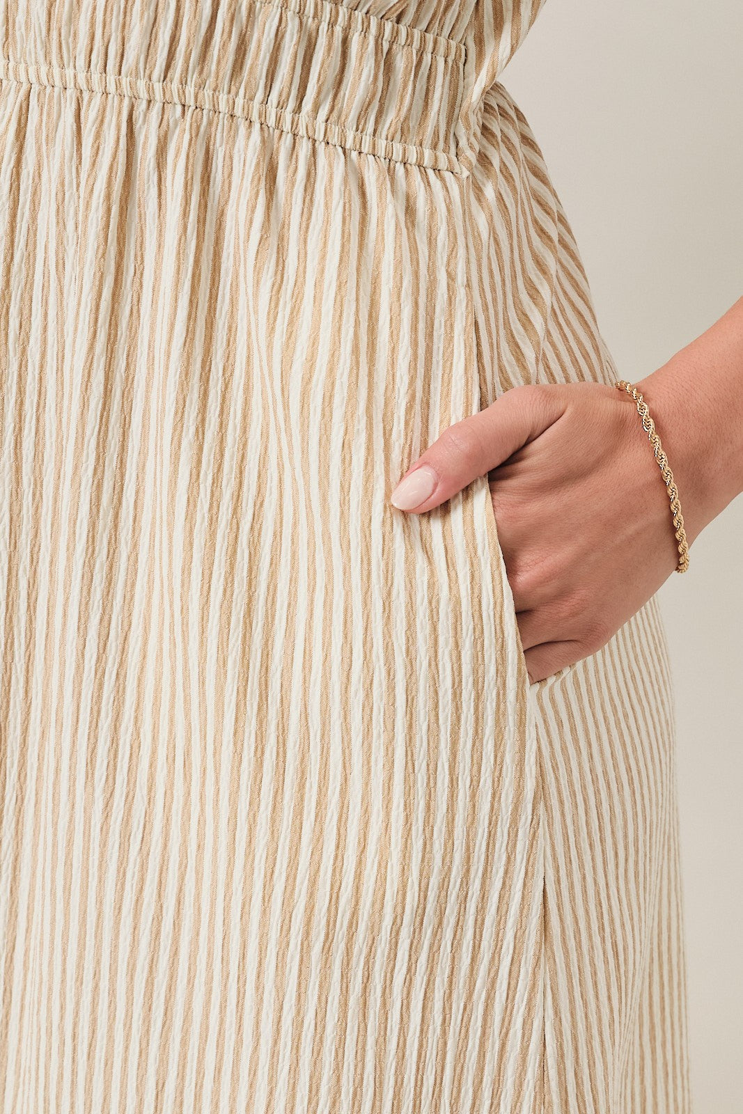 woman wearing a cream and light beige striped midi skirt with an elastic waistband and pockets
