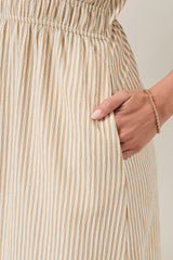 woman wearing a cream and light beige striped midi skirt with an elastic waistband and pockets