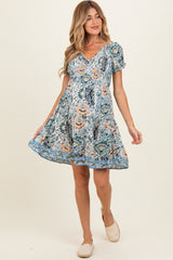 woman wearing a floral print maternity dress with short sleeves and a flared skirt, showing her baby bump