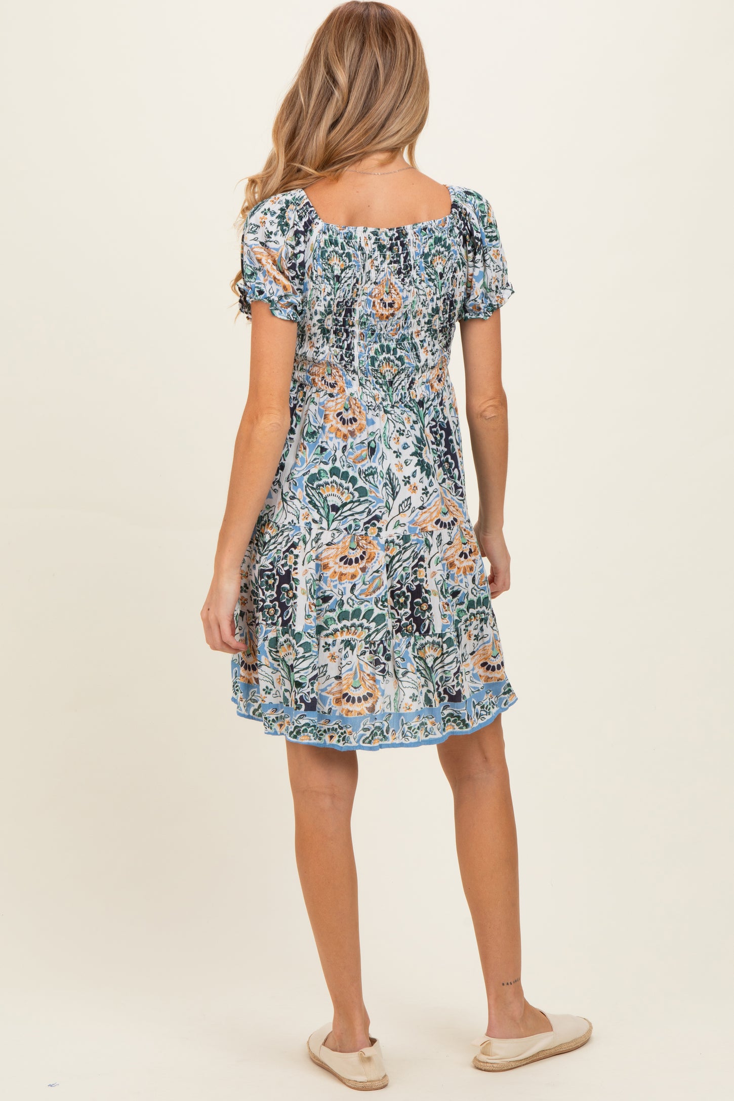 woman wearing a maternity floral short dress with puff sleeves and a relaxed fit, seen from the back
