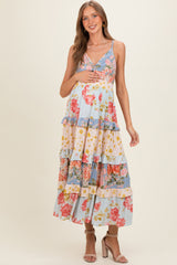 woman wearing a floral print maternity maxi dress with tiered ruffles and holding her baby bump