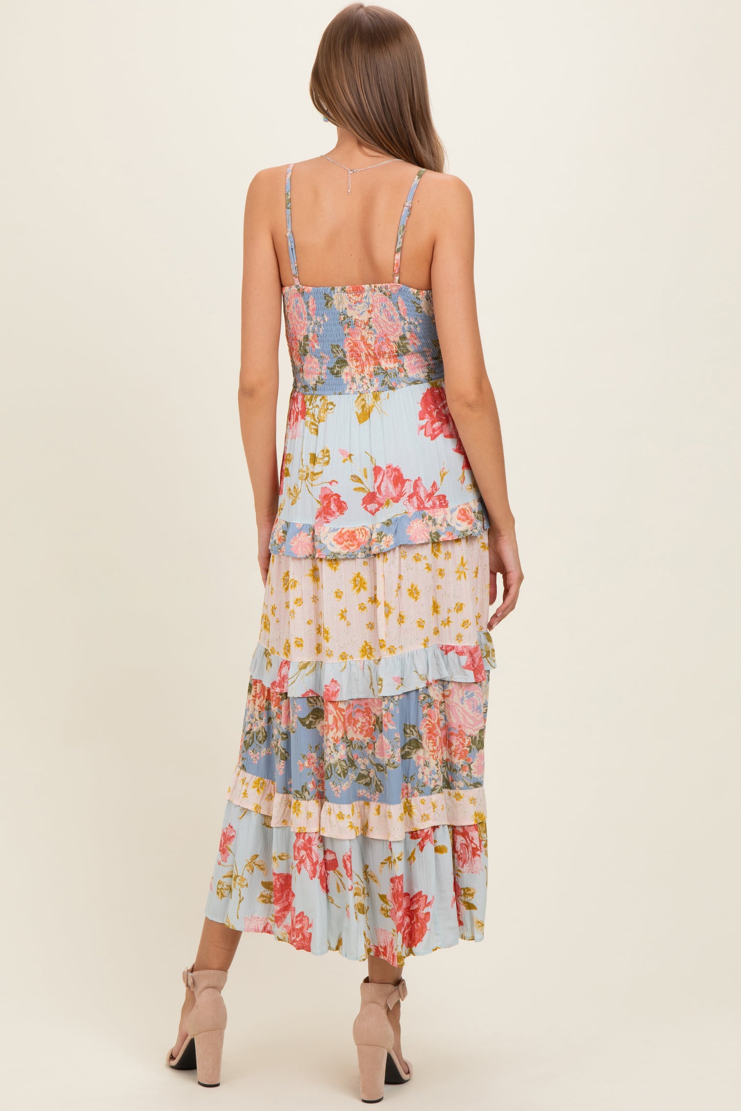 woman wearing a floral print maternity maxi dress with layered ruffles and spaghetti straps, showing the back view