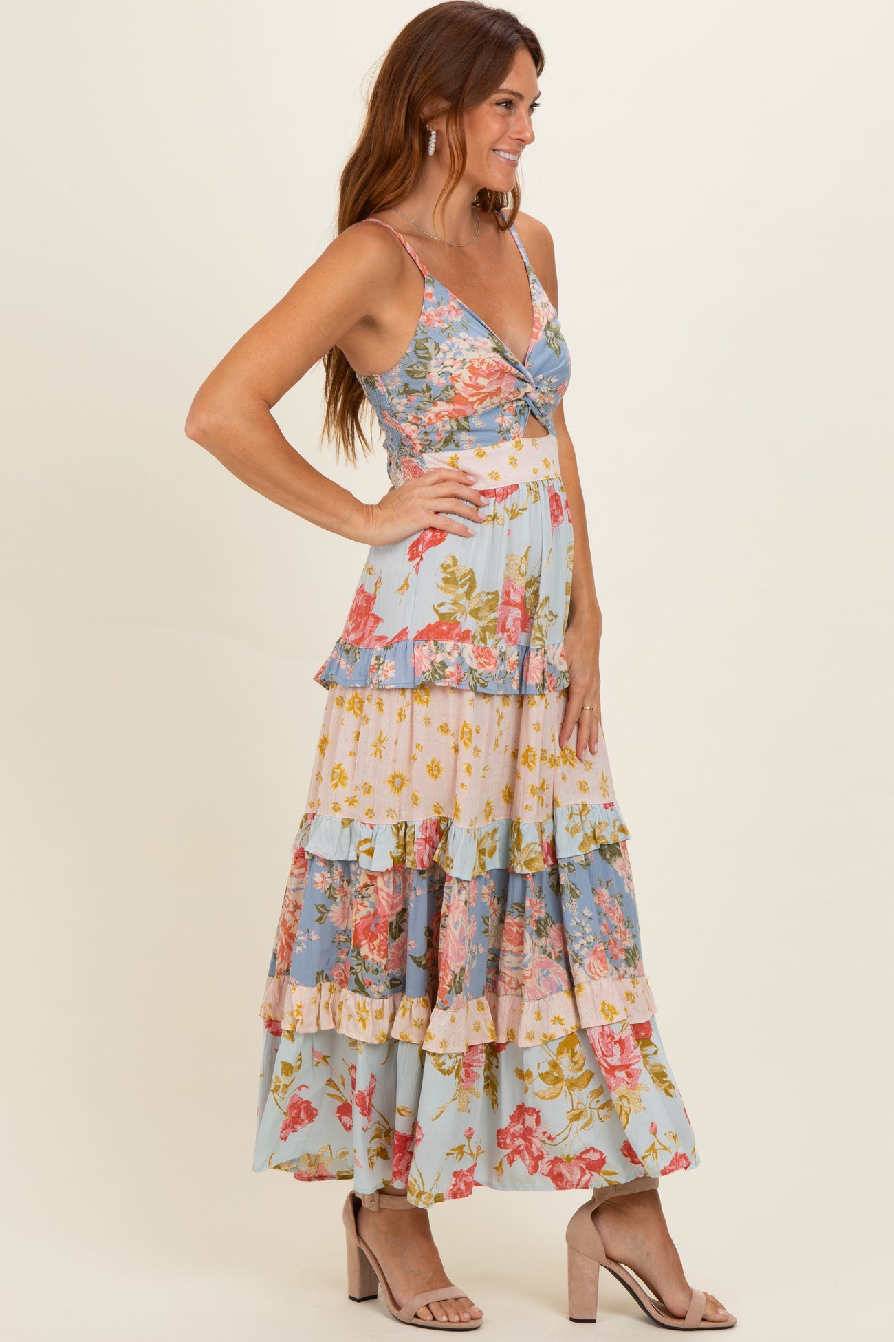 woman wearing a floral print maxi dress with a v-neckline and tiered ruffle hem, styled with nude heeled sandals