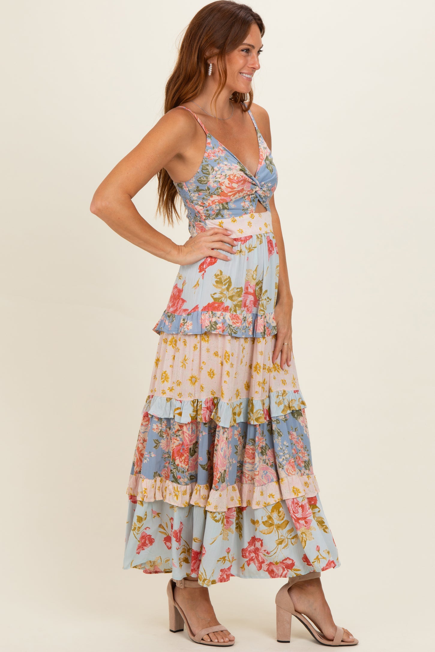woman wearing a floral print maxi dress with a v-neckline and tiered ruffle hem, styled with nude heeled sandals