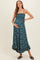 woman wearing a teal maternity maxi dress with floral print and a gathered bodice, holding her baby bump