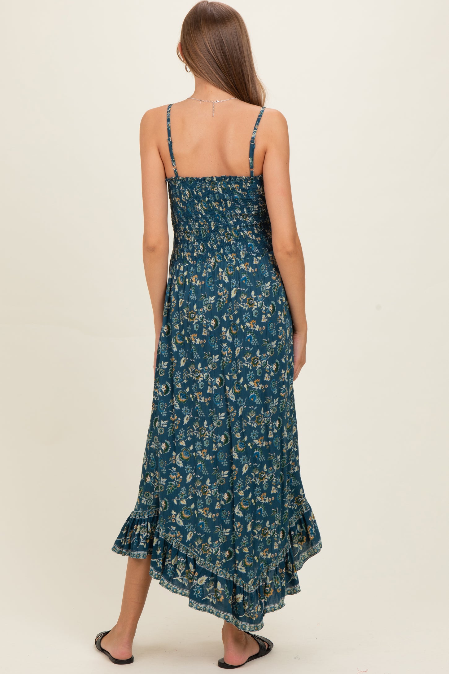 woman wearing a floral pattern maternity maxi dress with a ruffled hem and adjustable straps, seen from the back