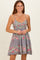 woman wearing a floral maternity dress with spaghetti straps and a fitted bodice, standing and smiling