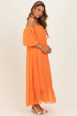 woman wearing an orange off-the-shoulder maxi dress with puff sleeves and a ruffled hem