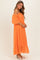 woman wearing an orange off-the-shoulder maxi dress with puff sleeves and a ruffled hem