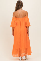 woman wearing an off-shoulder orange maxi dress with puff sleeves and a ruffled hem