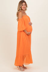 woman wearing an orange off-the-shoulder maternity dress and holding her baby bump